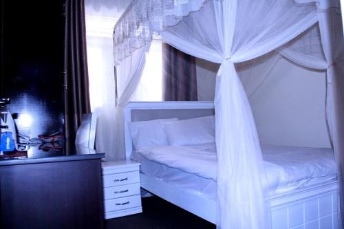 a bedroom with a canopy bed with white curtains at Bethel Resort & Hotels in Gulu