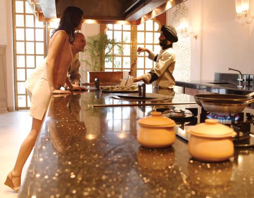 a woman in a kitchen preparing food in a kitchen at The Oberoi Rajvilas Jaipur in Jaipur