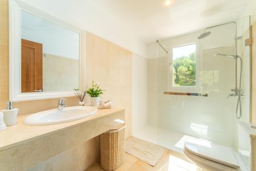 a white bathroom with a sink and a shower at Villa Cala Mesquida in Cala Mesquida