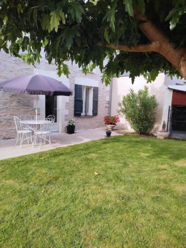 una mesa y sillas con una sombrilla en un patio en chambre la loire en La Daguenière