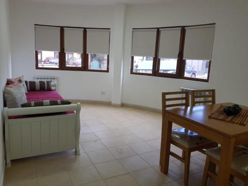 a living room with a couch and a table and windows at Alto Magallanes in Ushuaia