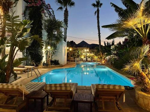 uma grande piscina com cadeiras e palmeiras em Minoa Apartments em Amoudara Herakliou