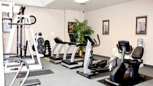 a gym with several tread machines and a clock at Marco LaGuardia Hotel & Suites in Queens