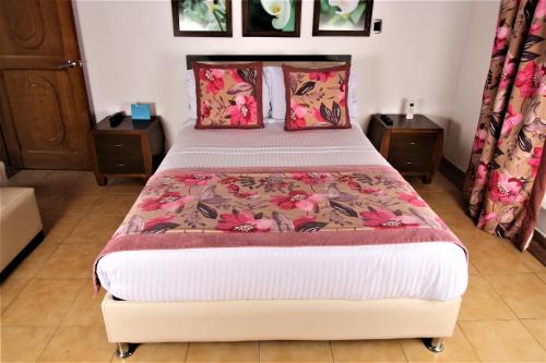 a bed in a bedroom with two tables and a bedspread at Amazilia Hotel in Pereira
