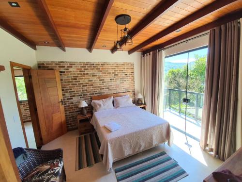 a bedroom with a bed and a large window at ATLANTIC FOREST ROOM in Angra dos Reis