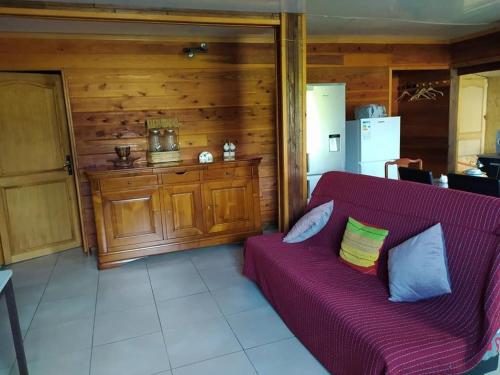 a living room with a purple couch and a kitchen at Ti' case la plaine in La Plaine des Palmistes