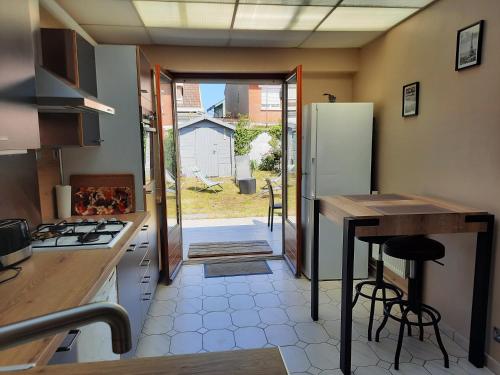 a kitchen with a refrigerator and a table in it at Maison Chez Lili à 200 m de la plage ,jardin privé et clos in Gravelines