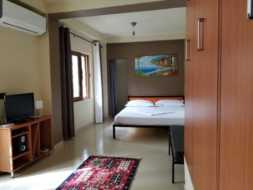 - une chambre avec un lit, une télévision et un tapis dans l'établissement Home Away From Home, à Saranda