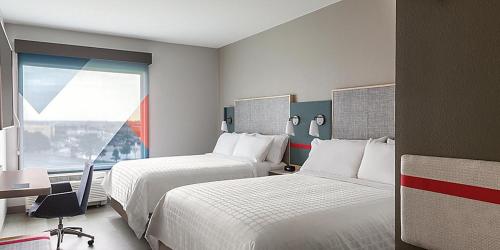 una camera d'albergo con due letti, una scrivania e una finestra di avid hotel Fayetteville West a Fayetteville