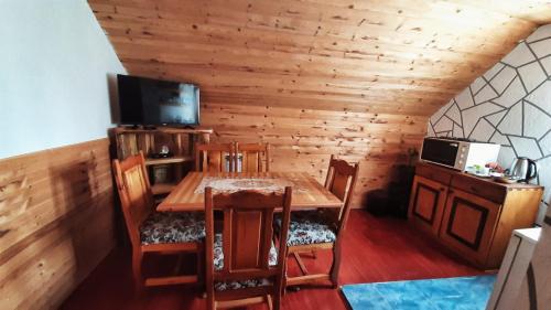 una sala da pranzo con tavolo in legno e TV di Woden apartment a Žabljak