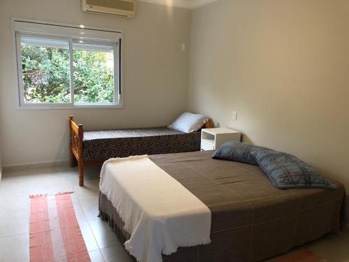 a bedroom with a bed and a window at Solar dos Cataventos: Linda Casa com Piscina e Jacuzi in Florianópolis