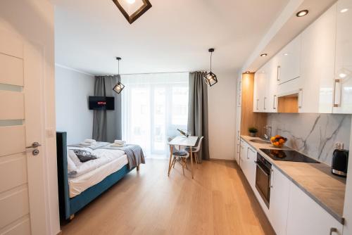 a bedroom with a bed and a kitchen with a table at Drwinka Park Apartment in Krakow
