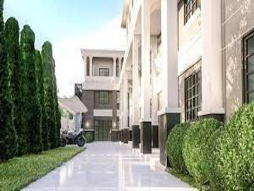 a walkway in front of a building with bushes at RoomQuest Rojana Industrial Estate area in Ban Nong Phai
