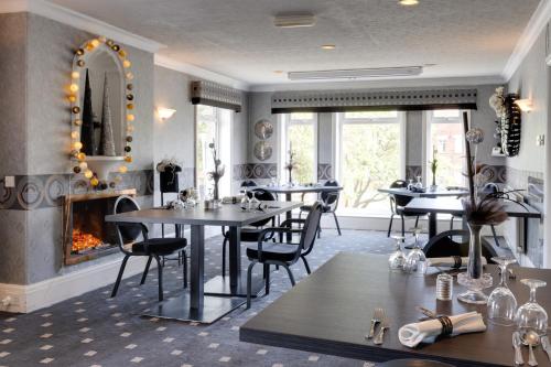 a restaurant with tables and chairs and a fireplace at Park Manor Hotel in Scarborough