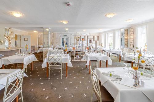 a dining room with white tables and chairs and white tablecloths at Park Manor Hotel in Scarborough