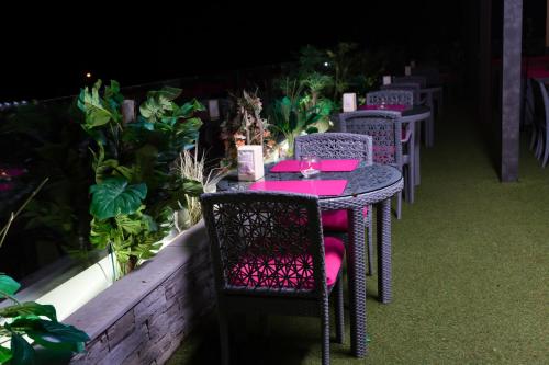 a table and chairs with pink tables and plants at Hotel du Golfe in Lomé
