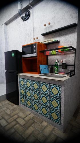 a kitchen with a counter with a microwave and a refrigerator at Lala Hostel in Banda Aceh