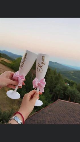 a person holding two white servers with pink flowers on them at Александрова вила 1 in Zlatograd