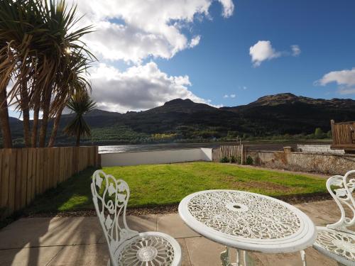 una mesa y sillas en un patio con vistas en Arrochar Alps Apartment en Arrochar