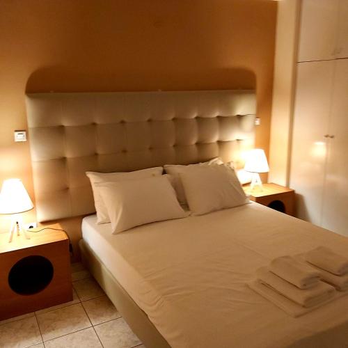 een slaapkamer met een groot wit bed met 2 lampen bij TSELIOS in Messini