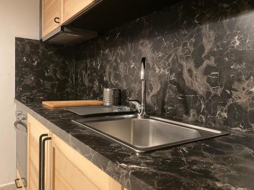 a kitchen with a sink and a black counter top at Davidana Deluxe Apartments in Nea Kallikrateia