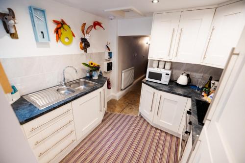 a small kitchen with white cabinets and a sink at Oh So Snug in Whalley