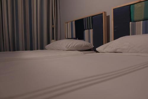 two beds with white sheets and pillows in a room at Giljana ensuite rooms shared terrace & kitchen in St Julian's
