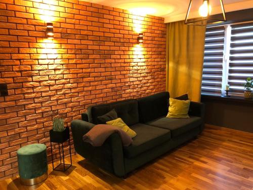 ein Wohnzimmer mit Sofa und Ziegelwand in der Unterkunft Studio Rynkowa in Stettin