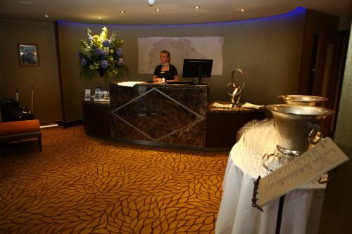 a woman standing at a reception desk in a hotel room at Best Western Heath Court Hotel in Newmarket
