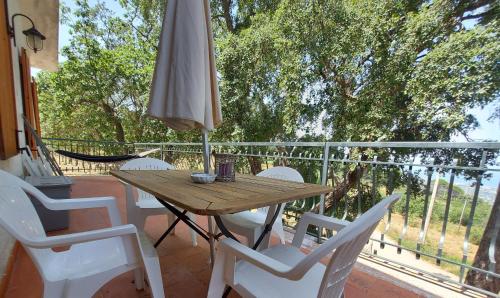 a wooden table and chairs on a balcony with an umbrella at Casa La Quercia- Tra Cefalù ed il Parco delle Madonie in Gratteri