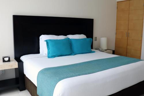 a bedroom with a large bed with blue pillows at Hotel Rio 1300 in Cuernavaca