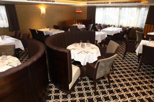 a dining room with tables and chairs with white table settings at Best Western Heath Court Hotel in Newmarket