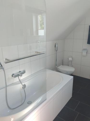 a white bathroom with a tub and a toilet at Jenny's Ferienwohnung in Monschau