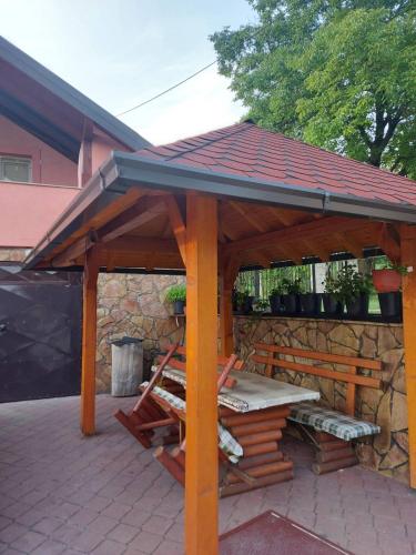 a wooden gazebo with a table and a stone wall at Villa Amir in Sarajevo