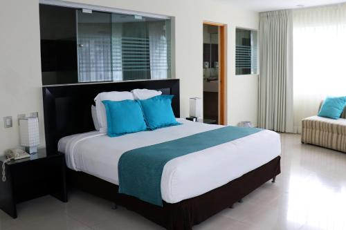 a bedroom with a large bed with blue pillows at Hotel Rio 1300 in Cuernavaca