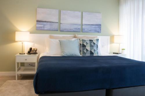 a bedroom with a blue bed with two lamps and a phone at Kavia Hotel do Largo in Cascais