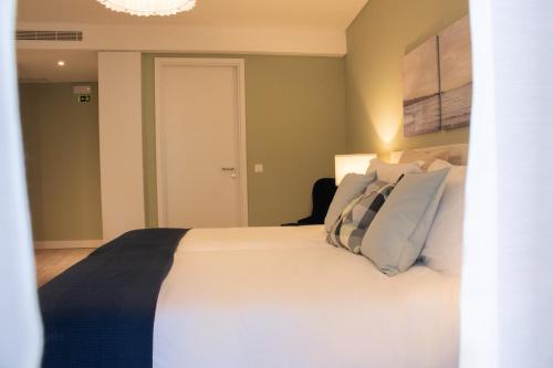 a bedroom with a bed with white sheets and pillows at Kavia Hotel do Largo in Cascais