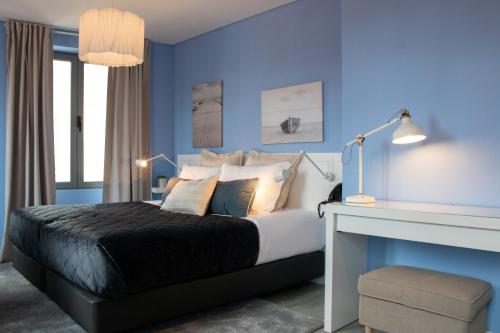 a blue bedroom with a bed and a desk at Kavia Hotel do Largo in Cascais