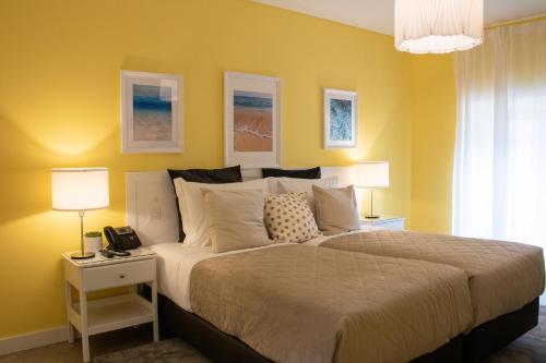 a bedroom with a large bed with yellow walls at Kavia Hotel do Largo in Cascais