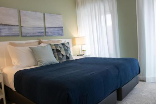 a bedroom with a large bed with a blue blanket at Kavia Hotel do Largo in Cascais