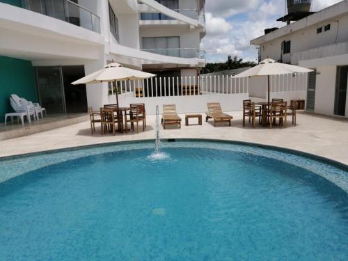 a large swimming pool with chairs and tables and umbrellas at Magico Apartamento Frente al Mar 3 Habitaciones FB73 in Coveñas