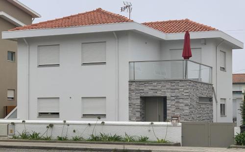 a white house with a red umbrella at Enjoy Esmoriz in Esmoriz