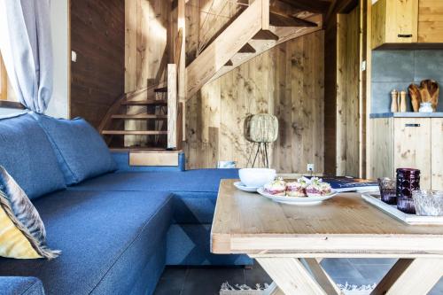 a living room with a blue couch and a wooden table at Domki Fox House z jacuzzi elektrycznym na wyłączność in Kościelisko