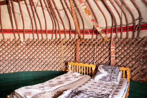 Bett in einer Jurte mit Kissen darauf in der Unterkunft Aidar Yurt Camp in Taldy