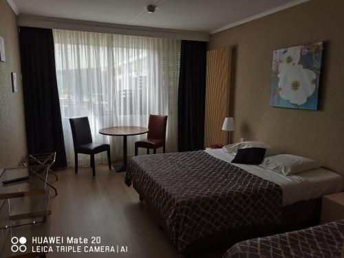 a hotel room with a bed and a table and chairs at Hôtel La Côte d'Or in Philippeville