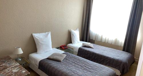 a hotel room with two beds and a window at Hôtel La Côte d'Or in Philippeville