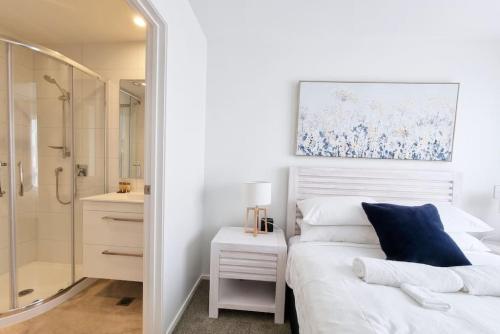 a bedroom with a white bed and a shower at Huntington Townhouse with Patio and Parking in Auckland