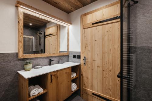 a bathroom with a sink and a mirror and a shower at Chalet Rich in Val Badia in San Martino in Badia