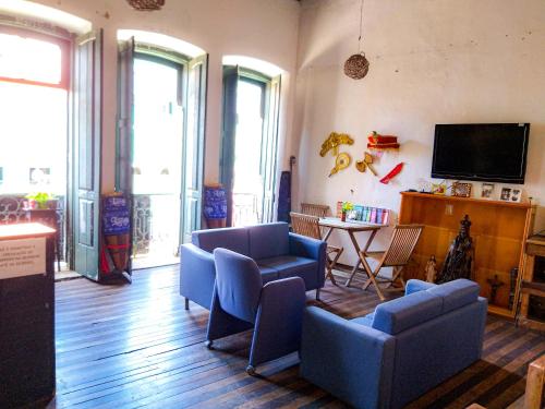 a living room with blue chairs and a tv at Hostel Ateliê Laroyê in Salvador