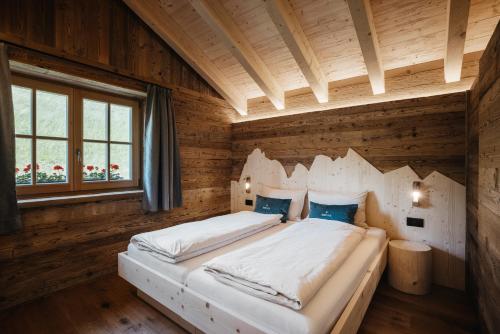 a bedroom with a large bed in a wooden room at Chalet Rich in Val Badia in San Martino in Badia
